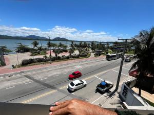 Eine Person schaut aus dem Fenster auf eine Straße mit Autos. in der Unterkunft Duplex em Itaúna 4min da Praia que ocorre o WSL, 1min da pista de skate do LS, pracinha com parque infantil, quadra de futebol, tudo isso a 1 min da duplex, perto do comércio, wi-fi super rápido, estacionamento gratuito, monitoramento 24hrs in Saquarema