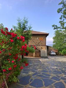 a house with red flowers and a stone driveway at Casa Cordovilla in Sequeros