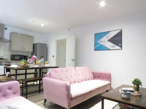 een woonkamer met een roze bank en een keuken bij Tudors eSuites - Central 4 bedroom house #14NS in Birmingham