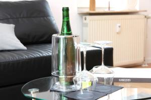 eine grüne Flasche und zwei Gläser auf dem Tisch in der Unterkunft Sophias Ferienwohnung Brilon in Brilon