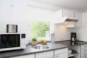 eine weiße Küche mit Spüle und Fenster in der Unterkunft Sophias Ferienwohnung Brilon in Brilon + 13 Fotos