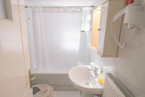 a white bathroom with a sink and a shower at TripoliStay in Tripolis