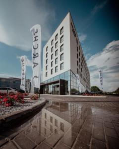 a large white building with a sign in front of it at Arche Hotel Lotnisko Gdańsk in Gdańsk-Rębiechowo
