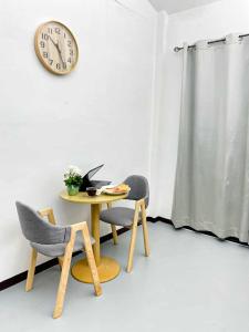 ein Tisch und zwei Stühle und eine Uhr an der Wand in der Unterkunft Wasana Village Phutoei in Ban Phu Toei