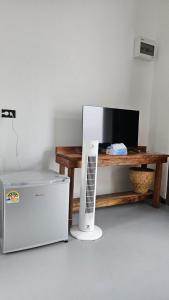 Ein Fernseher steht neben einem Tisch mit einem Kühlschrank. in der Unterkunft Wasana Village Phutoei in Ban Phu Toei