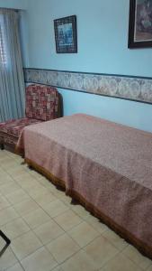 ein Bett und ein Stuhl in einem Zimmer in der Unterkunft Atlántico Peatonal in Necochea