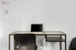 a glass desk with a laptop on top of it at Bright & Modern Room in Brixton - Shared Bathroom in London