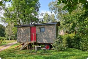 ein winziges Haus mit roter Tür auf einem LKW in der Unterkunft Roulotte - Etat Nature in Magnières
