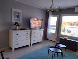 een slaapkamer met een witte ladekast, twee stoelen en een tv bij Järvenranta in Jämsä