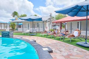 um grupo de pessoas sentadas em cadeiras de jardim ao lado de uma piscina em Domaine du lac bleu em Saint-Laurent du Maroni