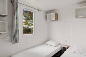 una stanza bianca con due letti e una finestra di Camping Le Domaine de la Marina a Messanges Altre 22 foto