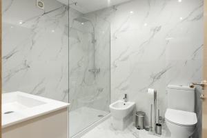 ein weißes Bad mit einer Dusche, einem WC und einem Waschbecken in der Unterkunft Miral Beachside 2 - by HD Properties in Caliços + 12 Fotos