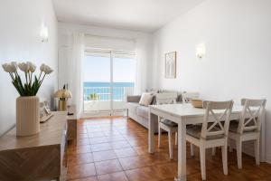 ein Esszimmer und ein Wohnzimmer mit Tisch und Stühlen in der Unterkunft Maresia - Front beach - Quarteira in Vilamoura