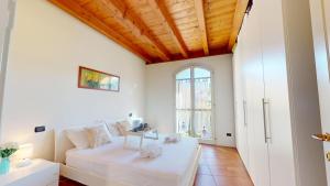 a living room with a white couch and a window at Borgo del Torchio C8 ByBookinggardalake in Manerba del Garda +22 photos