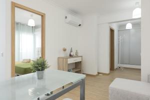 ein weißes Wohnzimmer mit einem Tisch und einem Spiegel in der Unterkunft Miral Beachside 4 - by HD Properties in Caliços