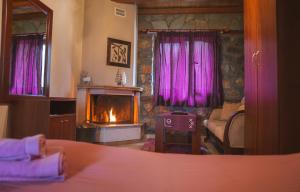 a bedroom with a fireplace and a bed with purple curtains at ΞΕΝΩΝΑΣ ΘΕΑ in Palaios Agios Athanasios