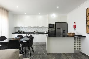 a kitchen with white cabinets and a table and chairs at Espadarte - Sea view by HD in Quarteira