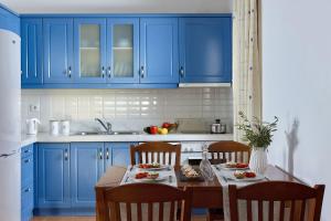 a kitchen with blue cabinets and a table with food on it at Ferienhaus In Geropotamos Mit Sonnenterrasse in Balíon