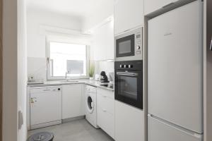 eine weiße Küche mit Mikrowelle und Geschirrspüler in der Unterkunft Miral Beachside 1 - by HD Properties in Caliços