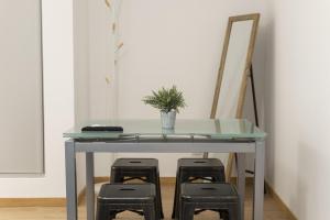 ein Glastisch mit drei Hockern darunter mit einer Pflanze in der Unterkunft Miral Beachside 1 - by HD Properties in Caliços