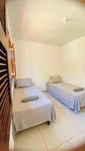 zwei Betten in einem Zimmer mit weißen Wänden in der Unterkunft Casa em condominio proximo ao beach park in Aquiraz + 17 Fotos