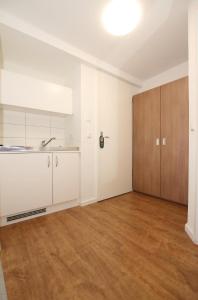 an empty kitchen with white cabinets and a wooden floor at Apartment Hotel am Sand 24H Self Check-in in Hamburg +22 photos