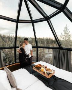 a couple kissing in a room with a tray of food at SkyView Igloo Resort in Rovaniemi