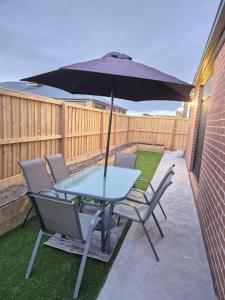 a table and chairs with an umbrella on a patio at Cosy Home in Melton South in Melton South