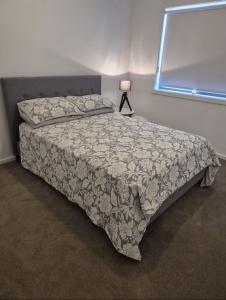 a bedroom with a bed with a blanket and a lamp at Cosy Home in Melton South in Melton South +9 photos