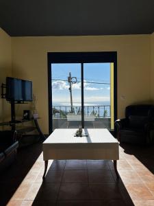 ein Wohnzimmer mit Tisch und großem Fenster in der Unterkunft Fernanda's House in Ribeira Brava