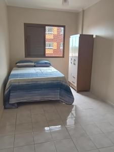 ein Schlafzimmer mit einem Bett und einem Fenster in der Unterkunft Apartamento com piscina Vista Mar - Mongaguá in Mongaguá