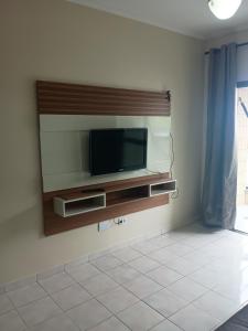 ein Wohnzimmer mit einem Fernseher an der Wand in der Unterkunft Apartamento com piscina Vista Mar - Mongaguá in Mongaguá