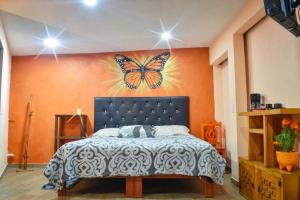 - une chambre dotée d'un lit avec un papillon sur le mur dans l'établissement Departamento céntrico con terraza, à Mineral de Angangueo