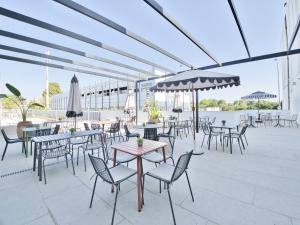 a patio with tables and chairs and umbrellas at Canvas Sevilla Lago in Seville