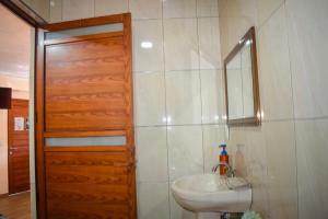 La salle de bains est pourvue d'un lavabo et d'une porte en bois. dans l'établissement Departamento céntrico con terraza, à Mineral de Angangueo