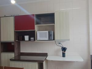 a kitchen with a counter with a microwave in it at Apartamento com piscina Vista Mar - Mongaguá in Mongaguá