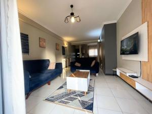 a living room with blue couches and a tv at Carihaven Homz Najjera in Buwate
