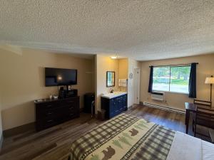 ein Schlafzimmer mit einem Bett, einem Schreibtisch und einem Fernseher in der Unterkunft Winthrop Inn in Winthrop