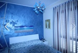 ein blaues Schlafzimmer mit einem Bett und einer blauen Wand in der Unterkunft La Casa in riva al Mare in Roccalumera