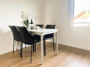 a dining room table with black chairs and a white table at 3-Zimmer-Apartment mit Terrasse, 5 Min zu Bahn & Shops in Luterbach