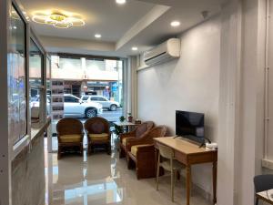 a waiting room with chairs and a table and a television at Starhouse in Hat Yai