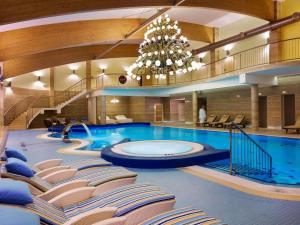 une grande piscine avec des chaises et un lustre dans l'établissement Hotel Mercure Krynica Zdrój Resort&Spa, à Krynica-Zdrój