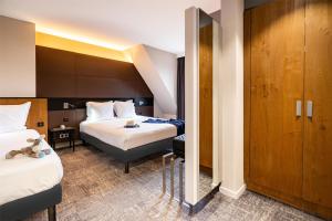 a hotel room with two beds and a closet at Hotel L'Europe Colmar, BW Signature Collection in Colmar