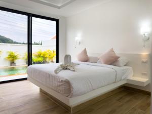 una camera bianca con un grande letto con una grande finestra di Stylish 3BR Pool Villa Lawan Villa (LWV1) a Ban Na Bon Altre 10 foto