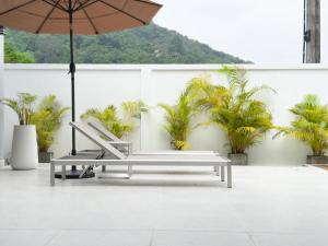 un patio con ombrellone, panca e palme di Stylish 3BR Pool Villa Lawan Villa (LWV1) a Ban Na Bon