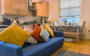 eine blaue Couch mit bunten Kissen darauf in der Küche in der Unterkunft Leamington Spa Warwick Place Apartments in Leamington Spa