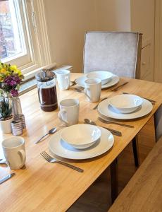 einem Holztisch mit Tellern und Utensilien darauf in der Unterkunft Leamington Spa Warwick Place Apartments in Leamington Spa