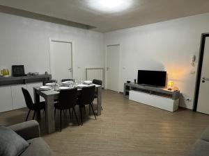 ein Wohnzimmer mit einem Tisch mit Stühlen und einem TV in der Unterkunft Ulisse Fashion Suites - Ecosole Real Estate in Serravalle Scrivia