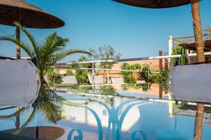 a swimming pool with two chairs and an umbrella at Riad Le Coq Berbère in Marrakesh