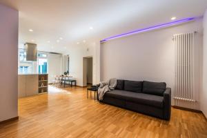 ein Wohnzimmer mit einer schwarzen Couch und einer Küche in der Unterkunft Casa Naonis comfort and relax in the historic center in Pordenone